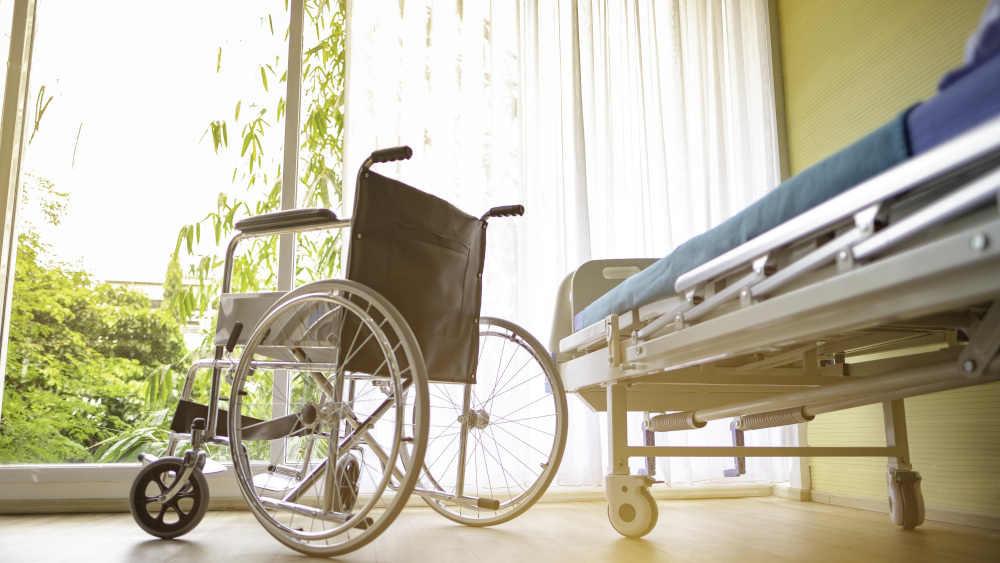 wózek inwalidzki stojący przy łóżku ortopedycznym 