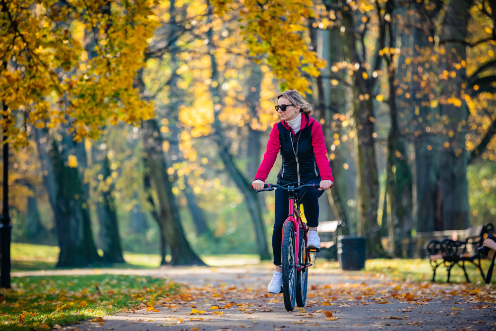 kobieta jadąca na rowerze w parku jesienią